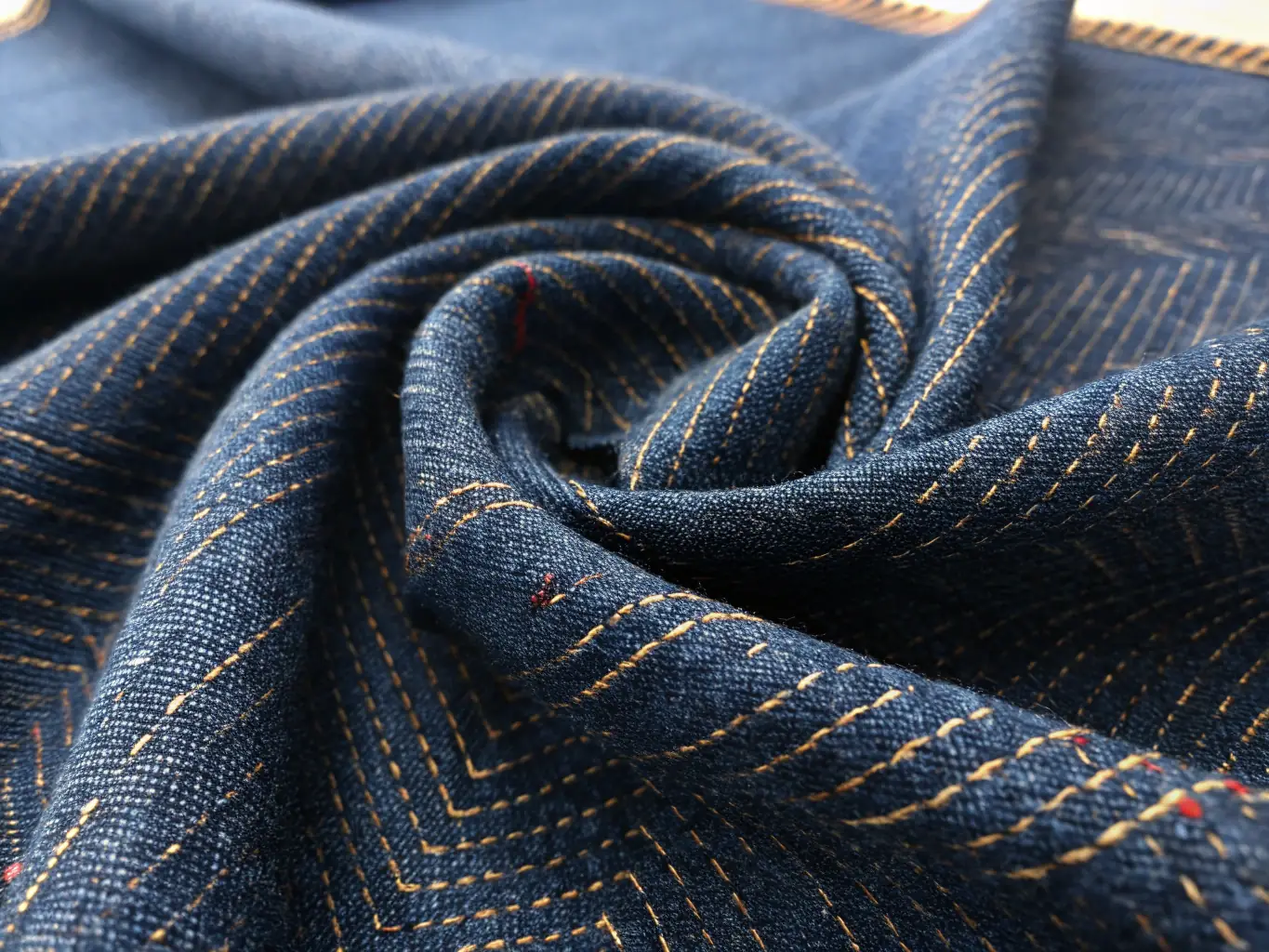 Close-up of a piece of durable denim fabric, showcasing its sturdy weave and classic texture. The image emphasizes the fabric's resilience and versatility, highlighting its suitability for everyday wear and rugged use.